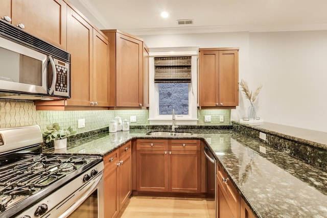 kitchen featuring stainless steel appliances, tasteful backsplash, sink, and dark stone counters