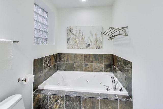 bathroom featuring tiled bath and toilet