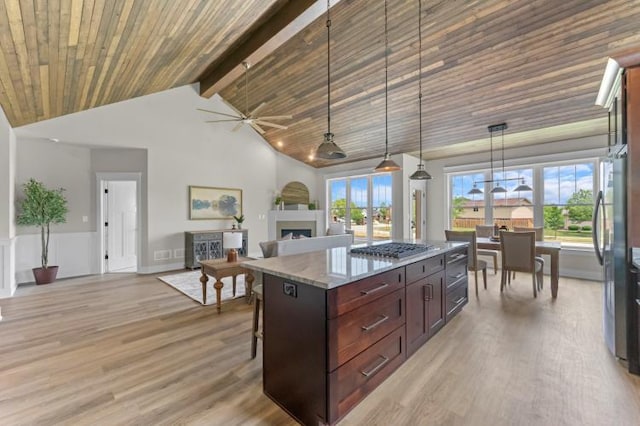 kitchen featuring wood ceiling, decorative light fixtures, a kitchen breakfast bar, a kitchen island, and light stone counters