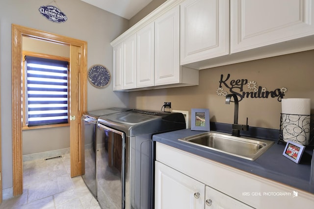 clothes washing area with cabinets, washing machine and clothes dryer, and sink