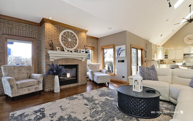 living room with brick wall, a wealth of natural light, dark hardwood / wood-style floors, and a brick fireplace