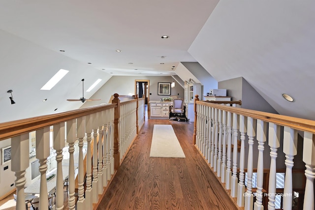 corridor featuring vaulted ceiling with skylight and wood-type flooring