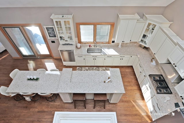 kitchen with stainless steel dishwasher, white cabinets, a kitchen bar, and sink