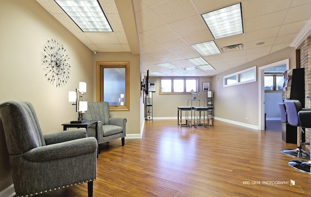 sitting room with hardwood / wood-style floors and a drop ceiling