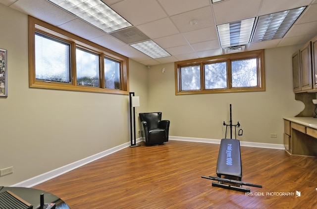 workout room with a paneled ceiling and hardwood / wood-style flooring