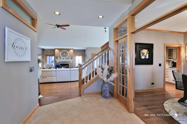 stairs featuring a brick fireplace, hardwood / wood-style flooring, and ceiling fan