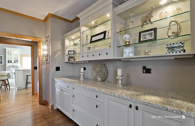 bar featuring white cabinets, light stone counters, and hardwood / wood-style flooring