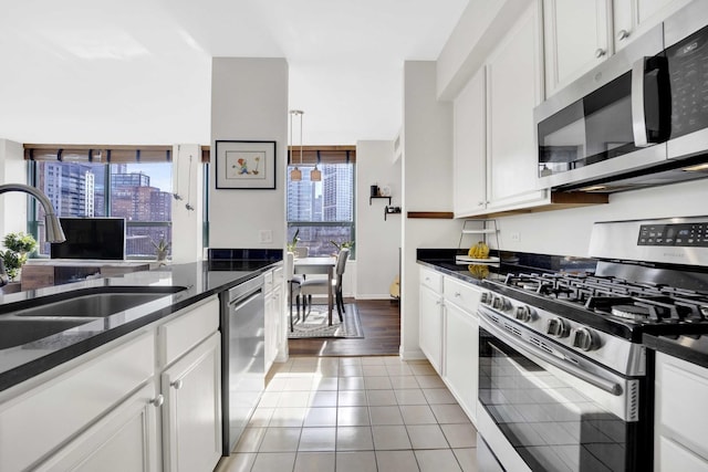 kitchen featuring decorative light fixtures, sink, white cabinetry, appliances with stainless steel finishes, and light tile patterned floors