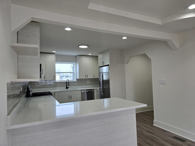 kitchen with sink, dark wood-type flooring, stainless steel appliances, tasteful backsplash, and kitchen peninsula