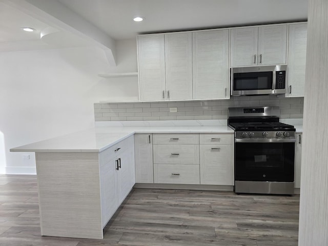 kitchen featuring appliances with stainless steel finishes, white cabinets, and kitchen peninsula