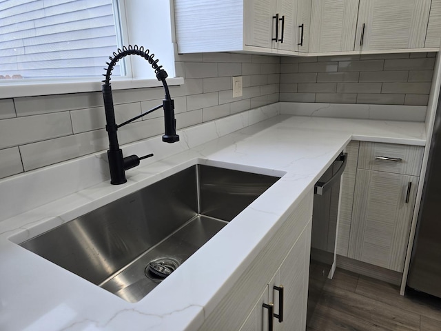 kitchen featuring light stone counters, dark hardwood / wood-style floors, sink, and decorative backsplash