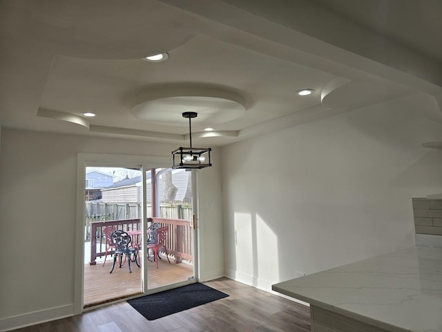 unfurnished dining area featuring an inviting chandelier, wood-type flooring, and a tray ceiling