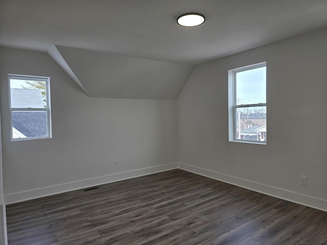 additional living space with vaulted ceiling and dark hardwood / wood-style flooring