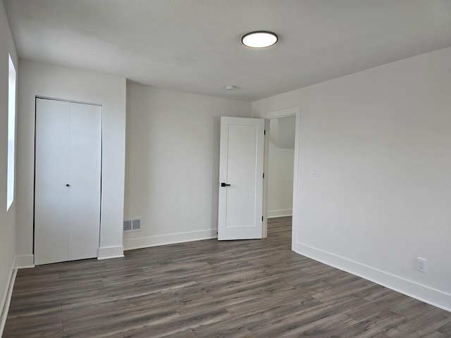 unfurnished bedroom featuring dark hardwood / wood-style flooring and a closet