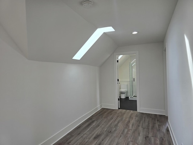 additional living space with dark wood-type flooring and vaulted ceiling with skylight