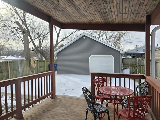 snow covered deck featuring an outbuilding and a garage