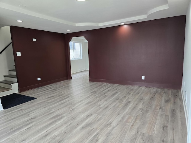 unfurnished room with a raised ceiling and light hardwood / wood-style floors