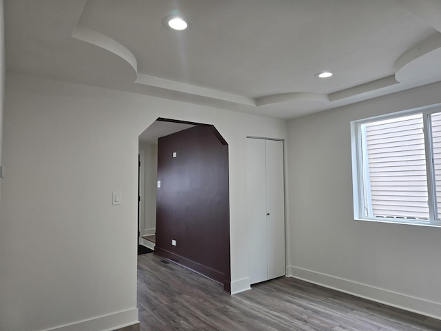 unfurnished room featuring a tray ceiling and dark hardwood / wood-style flooring