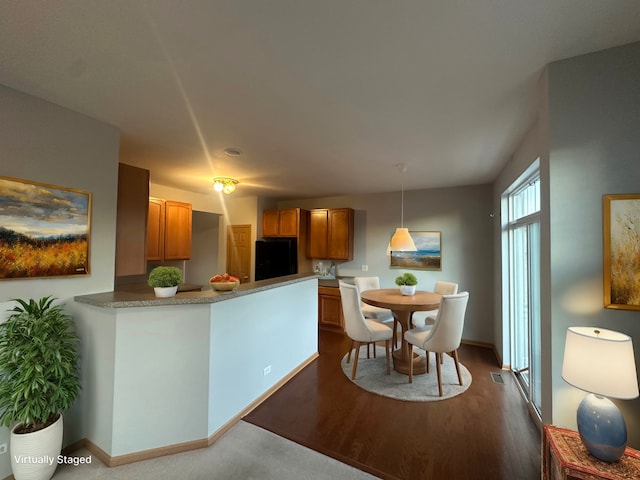 kitchen featuring hanging light fixtures, kitchen peninsula, refrigerator, and dark wood-type flooring