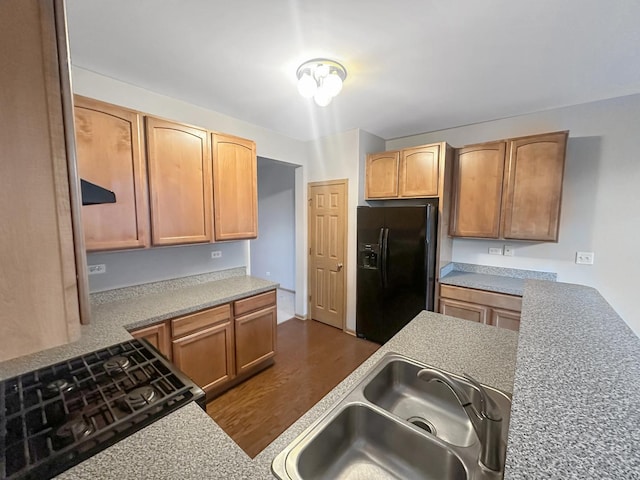 kitchen featuring black refrigerator with ice dispenser and sink