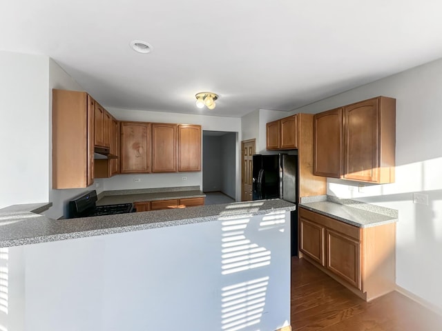 kitchen with hardwood / wood-style floors, black appliances, and kitchen peninsula