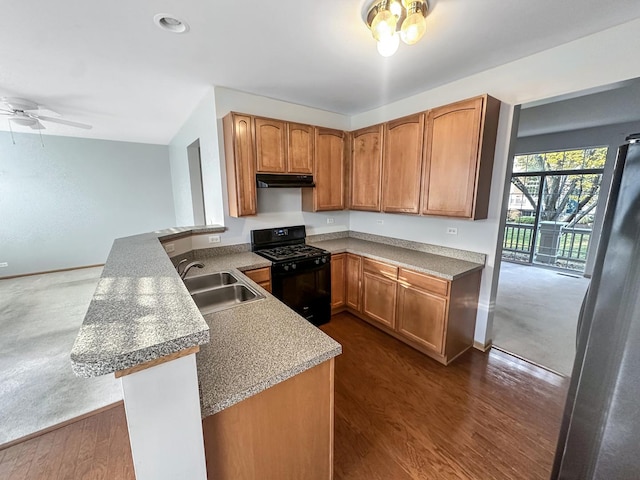 kitchen featuring dark hardwood / wood-style floors, gas stove, kitchen peninsula, sink, and stainless steel fridge