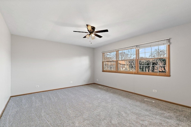 empty room featuring carpet floors, visible vents, baseboards, and a ceiling fan