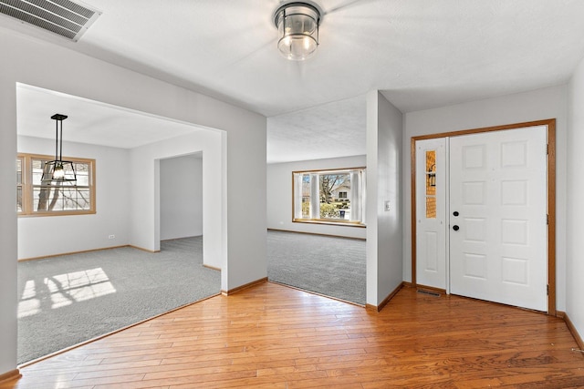 entrance foyer featuring light wood-type flooring, light colored carpet, visible vents, and a healthy amount of sunlight