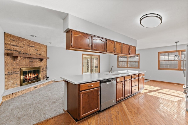 kitchen with dishwasher, hanging light fixtures, light countertops, light wood-type flooring, and a sink