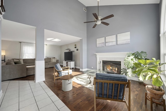 tiled living room featuring a tiled fireplace, ceiling fan, and a high ceiling