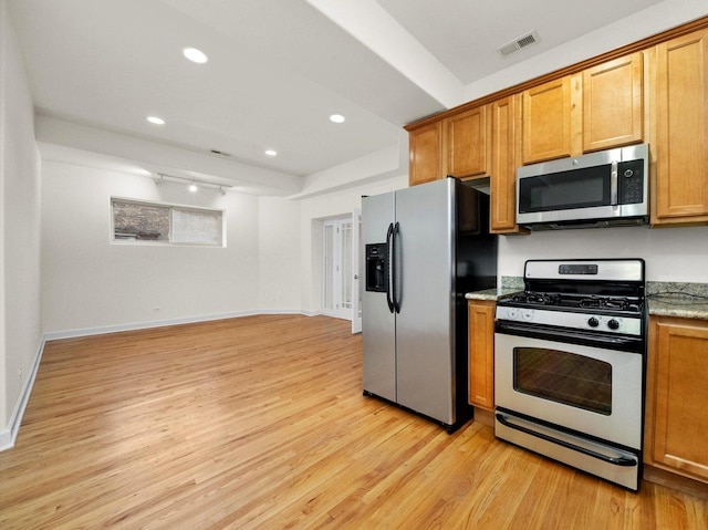 kitchen featuring light wood-type flooring, light stone countertops, and stainless steel appliances