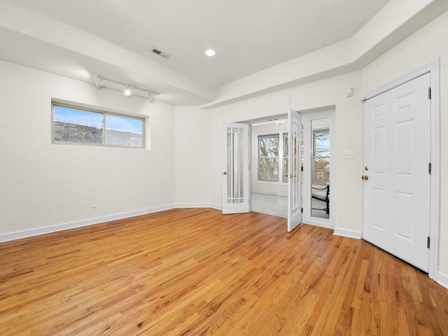 spare room featuring rail lighting and light hardwood / wood-style flooring