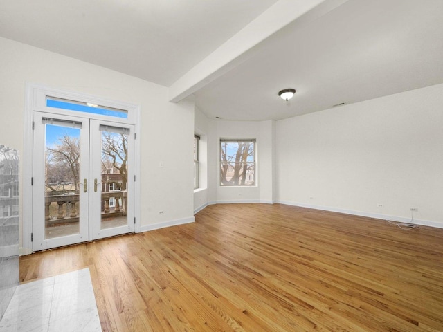 unfurnished room with french doors, light hardwood / wood-style flooring, and beamed ceiling