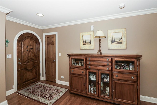 foyer entrance with baseboards, ornamental molding, dark wood-type flooring, and arched walkways