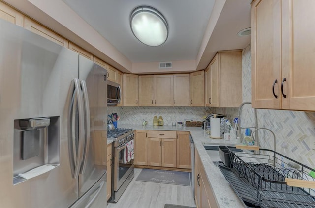 kitchen featuring light brown cabinetry, appliances with stainless steel finishes, and tasteful backsplash