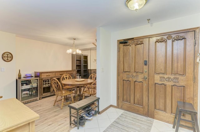 entryway with a notable chandelier, light tile patterned floors, and beverage cooler