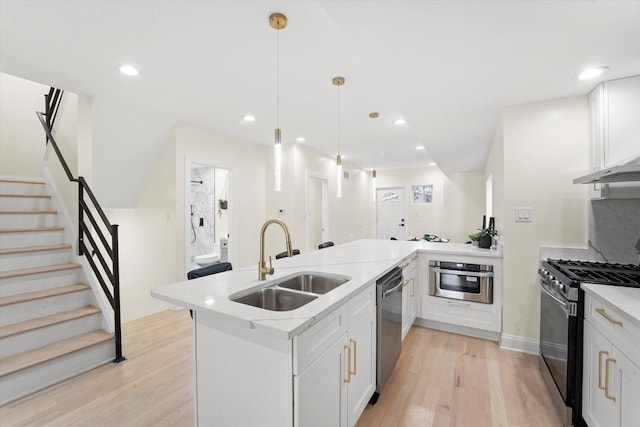 kitchen with appliances with stainless steel finishes, sink, white cabinetry, and pendant lighting