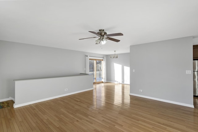 unfurnished room featuring ceiling fan with notable chandelier and hardwood / wood-style floors