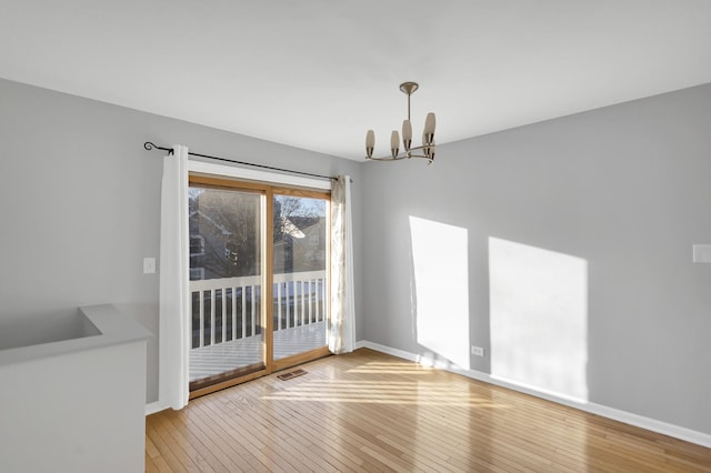 unfurnished dining area featuring a chandelier and hardwood / wood-style floors