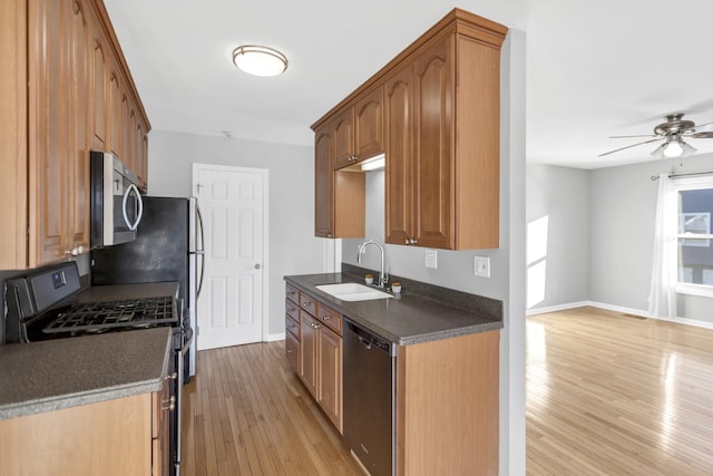 kitchen featuring dishwashing machine, gas stove, sink, ceiling fan, and light hardwood / wood-style flooring