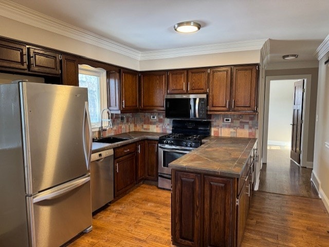 kitchen with tasteful backsplash, appliances with stainless steel finishes, sink, and light hardwood / wood-style floors