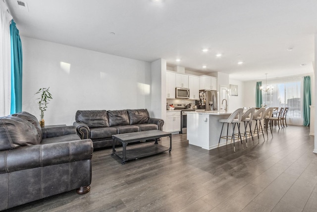 living room with sink, a notable chandelier, and dark hardwood / wood-style flooring