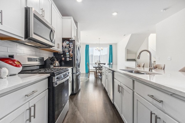 kitchen featuring appliances with stainless steel finishes, sink, white cabinetry, light stone countertops, and decorative backsplash