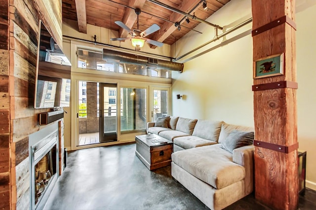 living room featuring a towering ceiling, wood ceiling, a large fireplace, ceiling fan, and beam ceiling