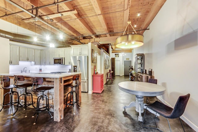 kitchen featuring pendant lighting, kitchen peninsula, appliances with stainless steel finishes, wood ceiling, and white cabinets