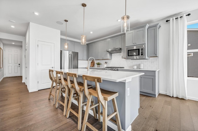 kitchen with decorative light fixtures, a kitchen breakfast bar, appliances with stainless steel finishes, and tasteful backsplash