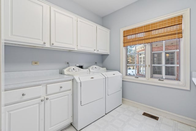 clothes washing area with washing machine and dryer and cabinets