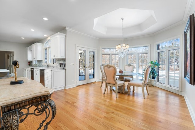 kitchen with pendant lighting, a tray ceiling, light wood-type flooring, white cabinets, and french doors