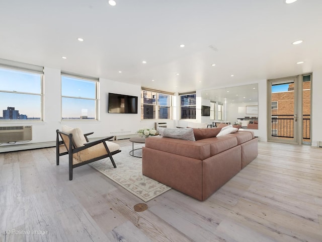 living room with a healthy amount of sunlight, light hardwood / wood-style floors, and a wall mounted AC