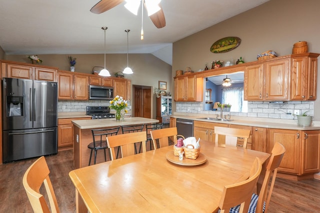 kitchen featuring appliances with stainless steel finishes, a center island, lofted ceiling, decorative backsplash, and sink